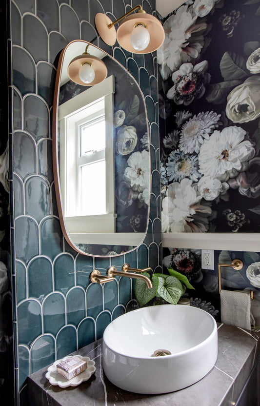 Dark Floral Wallpaper in powder room with blue tiles above sink and copper mirror and lamp.