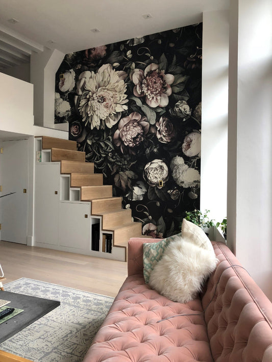 Modern interior with floral wallpaper design on a wall, pink sofa, and staircase.