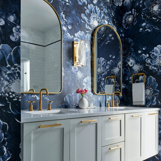 Bathroom with Ellie Cashman's Moonlight Meadow Blue Bloral wallpaper, white vanity, and gold fixtures.