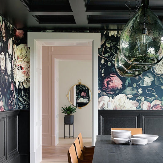 Dark Floral II Wallpaper by Ellie Cashman Design above brown wainscotting in dining room and large hanging lamps above table.